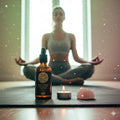 Person meditating with a bottle of Heart Chakra oil, candle, and crystal on a table.