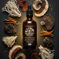 Bottle of Nootropic Gold Mushroom Blend tincture surrounded by dried mushrooms on a dark surface