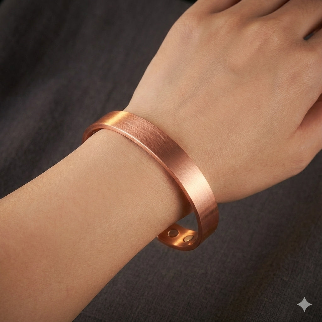Copper magnetic bracelet on a wrist against a dark background