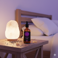 Bottle of lavender essential oil with a diffuser on a wooden table in a bedroom setting.
