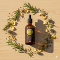 Bottle of Solar Plexus Tonic surrounded by herbs and flowers on a wooden surface