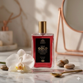 A bottle of Gold Face & Body Mist on a marble surface with an orchid and rocks.