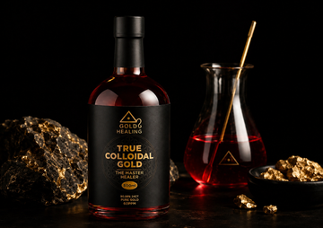 Gold Healing colloidal gold bottle with ruby red liquid, lab glassware and gold minerals on a black background.